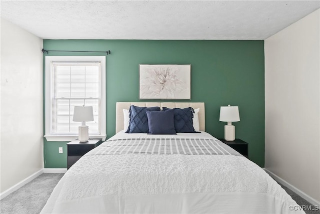 carpeted bedroom featuring an accent wall, a textured ceiling, and baseboards