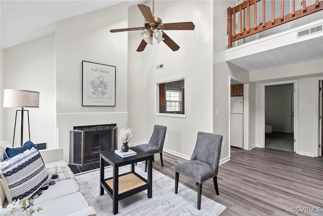 living area featuring a fireplace, wood finished floors, visible vents, and baseboards