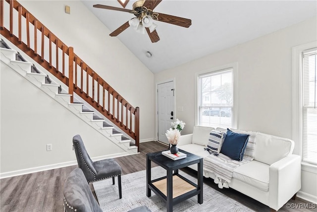 living area with lofted ceiling, ceiling fan, wood finished floors, baseboards, and stairway