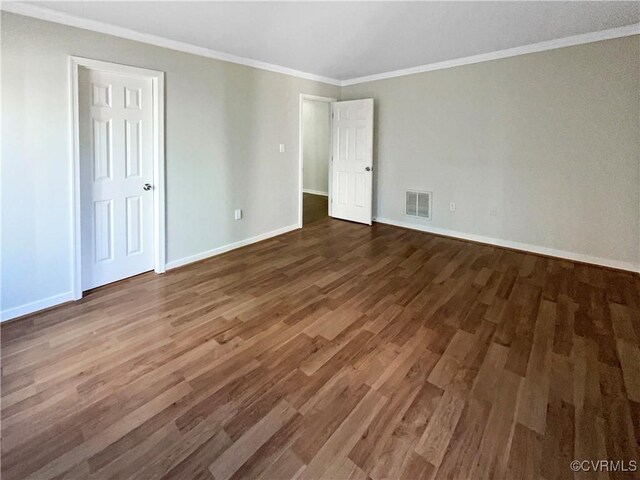 unfurnished bedroom with baseboards, crown molding, visible vents, and wood finished floors