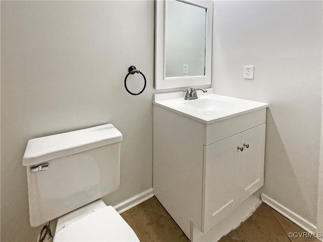 half bathroom with vanity, toilet, and baseboards