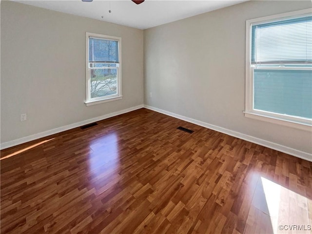 empty room with ceiling fan, baseboards, visible vents, and dark wood finished floors