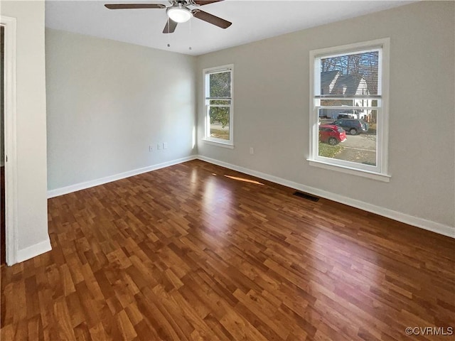 unfurnished room with ceiling fan, wood finished floors, visible vents, and baseboards