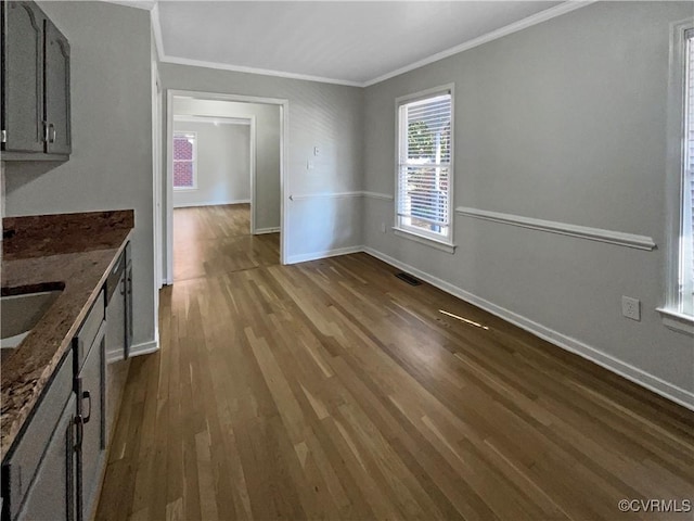 unfurnished dining area with ornamental molding, dark wood-style flooring, visible vents, and baseboards