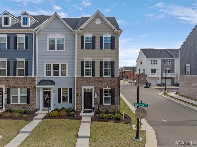 multi unit property featuring a front yard and brick siding