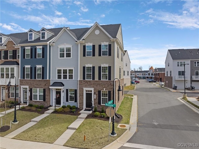 view of property featuring a front yard, a residential view, and brick siding