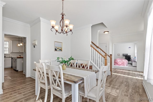 dining area featuring baseboards, wood finished floors, stairs, crown molding, and a chandelier