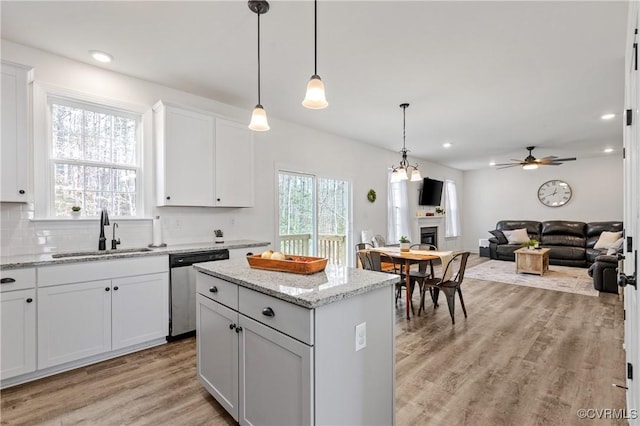 kitchen featuring a fireplace, backsplash, light wood-style flooring, a sink, and dishwasher