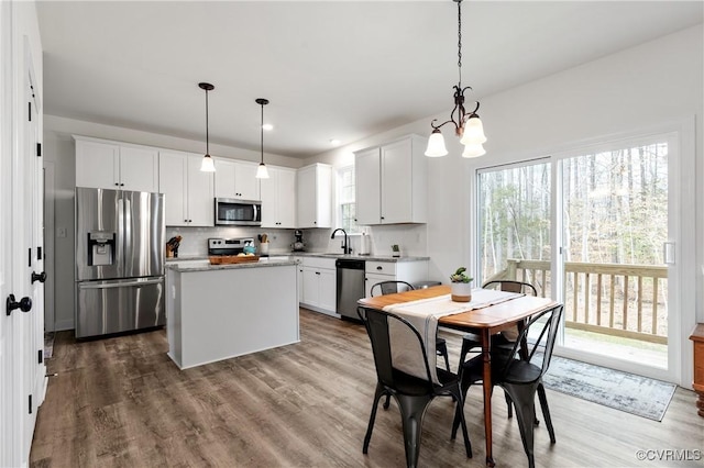 kitchen featuring tasteful backsplash, stainless steel appliances, a sink, and wood finished floors