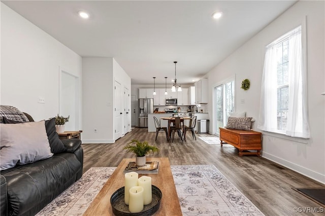 living room with baseboards, wood finished floors, and recessed lighting