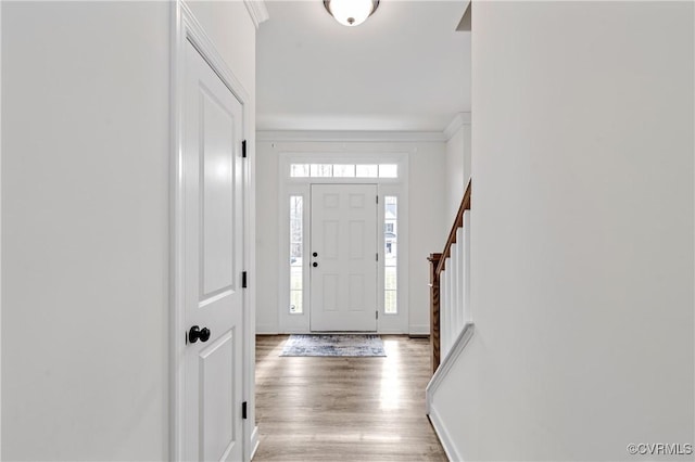 entrance foyer with baseboards, ornamental molding, and wood finished floors