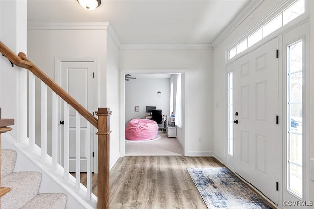 entrance foyer with stairway, baseboards, ornamental molding, and wood finished floors