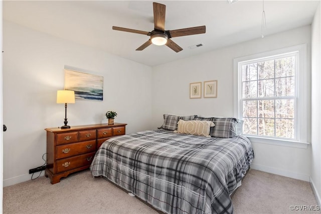 bedroom with light colored carpet, a ceiling fan, baseboards, visible vents, and attic access