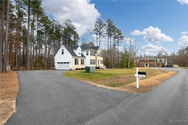 view of front of property featuring driveway, an attached garage, and a front lawn