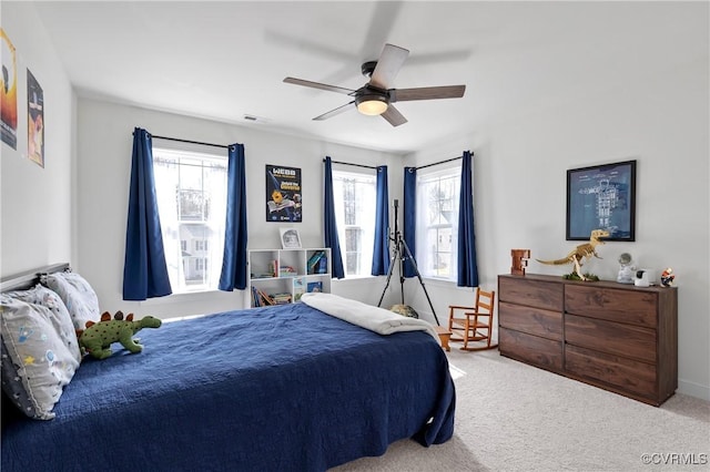 carpeted bedroom featuring baseboards, multiple windows, visible vents, and a ceiling fan