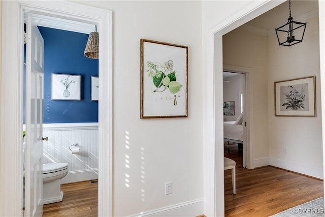 hall with a wainscoted wall and wood finished floors