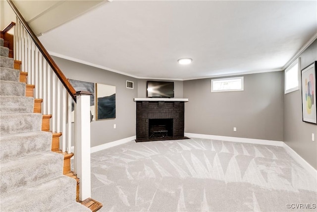 below grade area with baseboards, light carpet, a brick fireplace, and ornamental molding