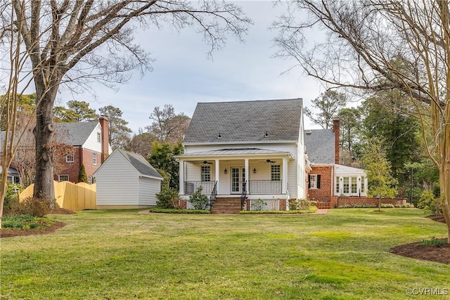 view of front facade featuring brick siding, a front lawn, fence, covered porch, and a ceiling fan