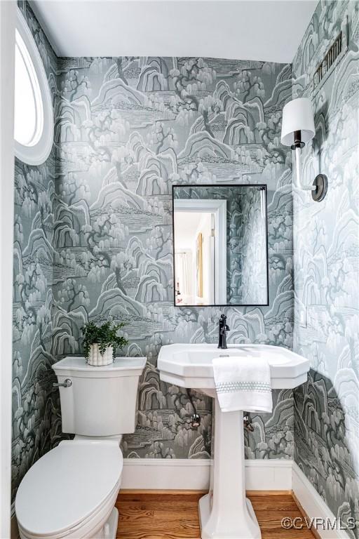 bathroom featuring baseboards, toilet, wood finished floors, and wallpapered walls