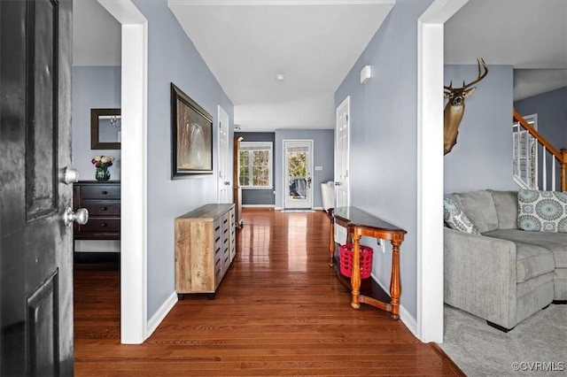 hallway featuring baseboards, stairway, and wood finished floors