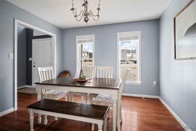 dining space with baseboards, a chandelier, and wood finished floors