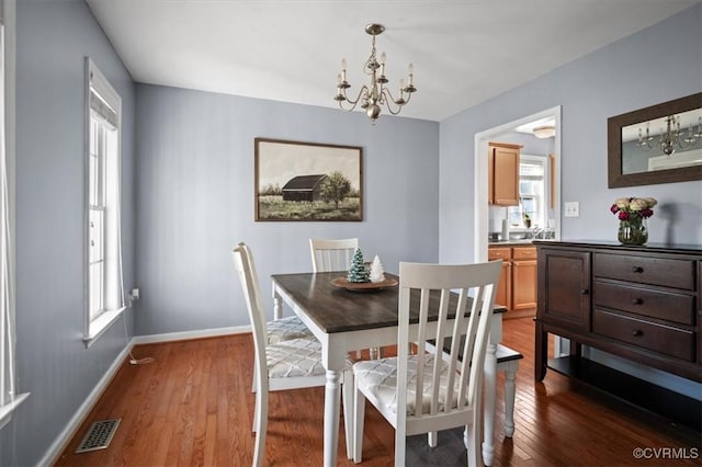 dining room with dark wood-style floors, a chandelier, visible vents, and baseboards