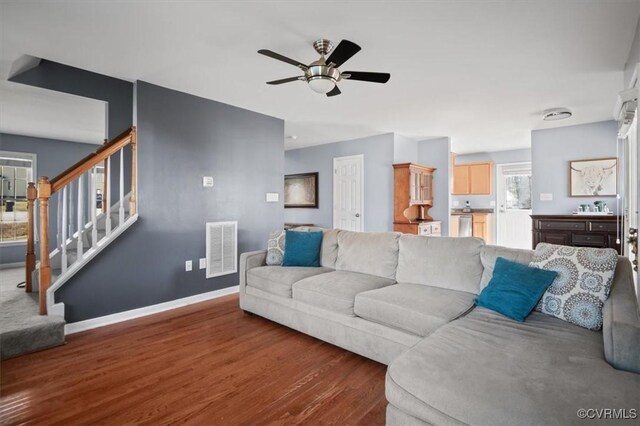 living area featuring visible vents, ceiling fan, wood finished floors, baseboards, and stairs