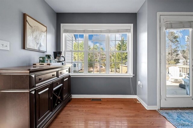 doorway with wood finished floors, visible vents, and baseboards