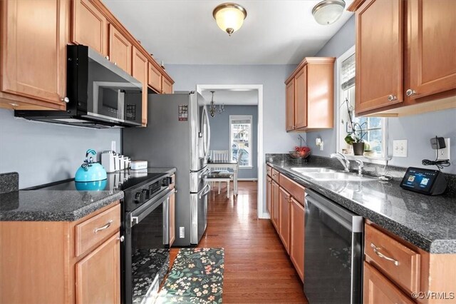 kitchen with stainless steel appliances, a wealth of natural light, a sink, and dark countertops