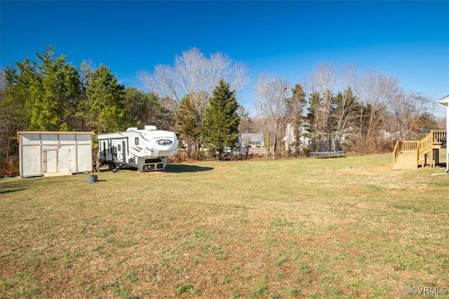 view of yard featuring a shed, a trampoline, and an outbuilding