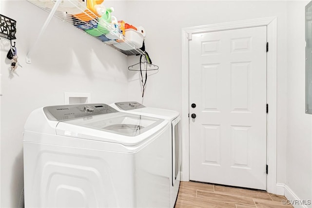 clothes washing area with baseboards, laundry area, washing machine and dryer, and wood tiled floor