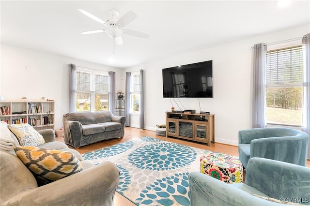 living area featuring ceiling fan, baseboards, and wood finished floors