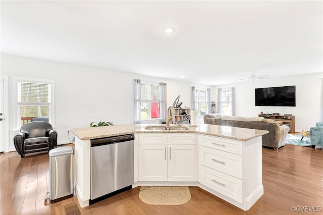 kitchen with a sink, light wood-style floors, open floor plan, and dishwasher