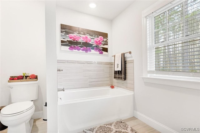 full bathroom with a healthy amount of sunlight, a garden tub, baseboards, and toilet