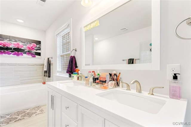 bathroom featuring visible vents, a sink, a garden tub, and double vanity