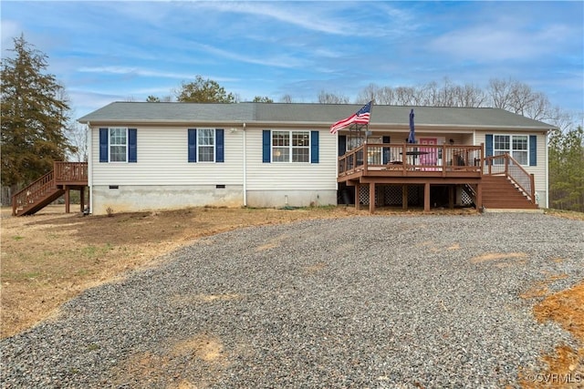 view of front of home with crawl space, stairs, a deck, and gravel driveway