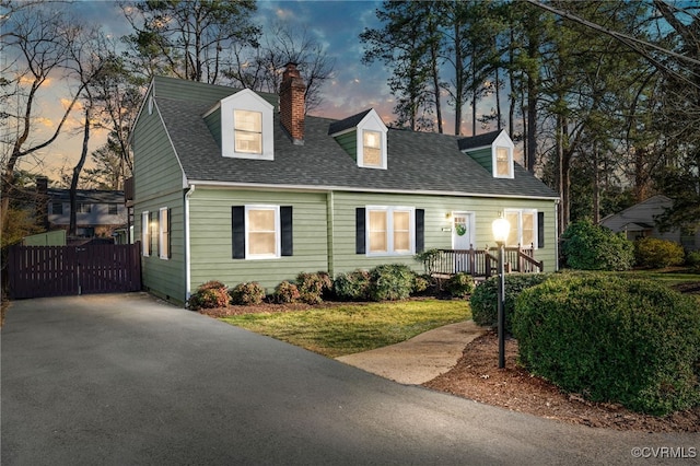 new england style home with roof with shingles and a chimney