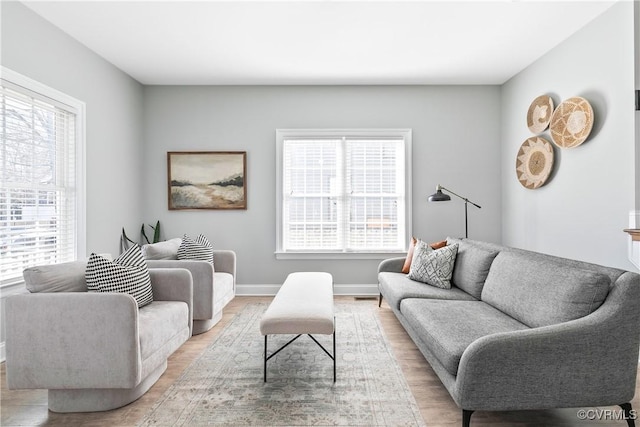 living room with baseboards, light wood-style floors, and a healthy amount of sunlight