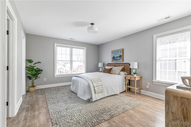 bedroom featuring wood finished floors, visible vents, and baseboards