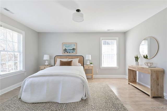 bedroom featuring light wood finished floors, baseboards, and visible vents