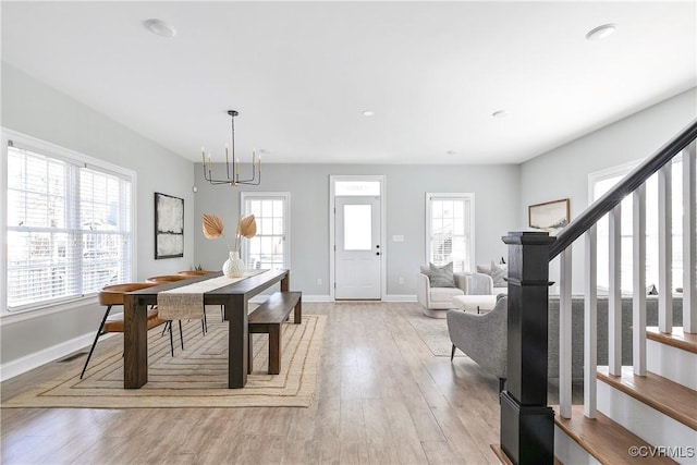 dining room featuring light wood-style flooring, stairs, baseboards, and a chandelier