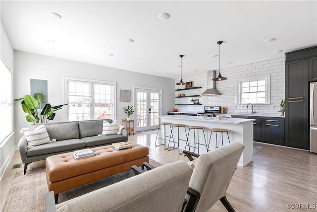 living area with light wood finished floors, french doors, and baseboards