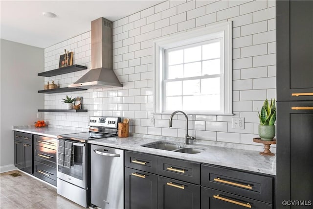 kitchen featuring tasteful backsplash, wall chimney exhaust hood, stainless steel appliances, open shelves, and a sink