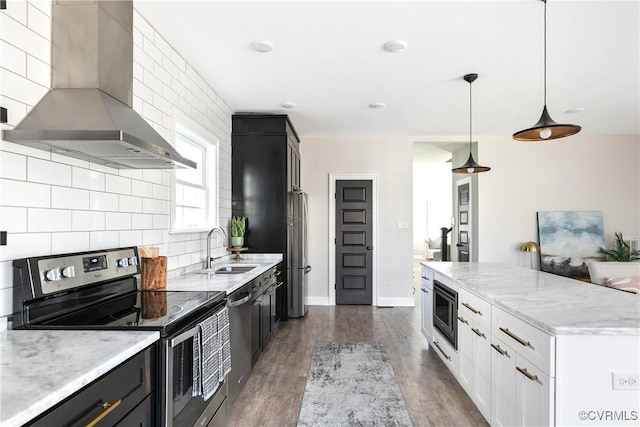 kitchen featuring tasteful backsplash, appliances with stainless steel finishes, dark wood-style flooring, wall chimney range hood, and a sink