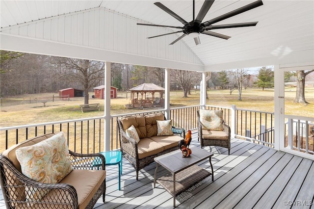 wooden deck featuring a gazebo, ceiling fan, a shed, an outdoor structure, and an outdoor living space