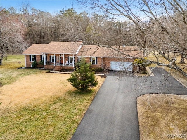 ranch-style home featuring aphalt driveway, a front yard, brick siding, and a porch