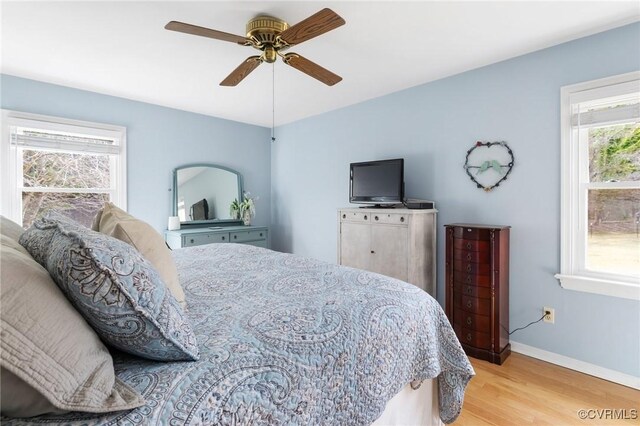 bedroom with light wood-style flooring, baseboards, and ceiling fan