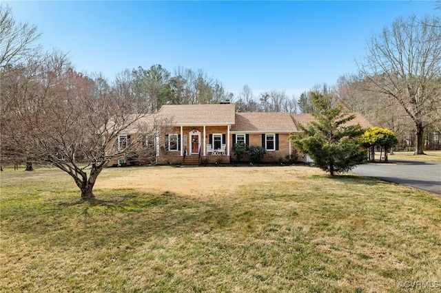 ranch-style house with a chimney, a front lawn, a porch, and brick siding