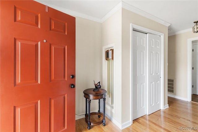 foyer featuring light wood finished floors, visible vents, ornamental molding, and baseboards