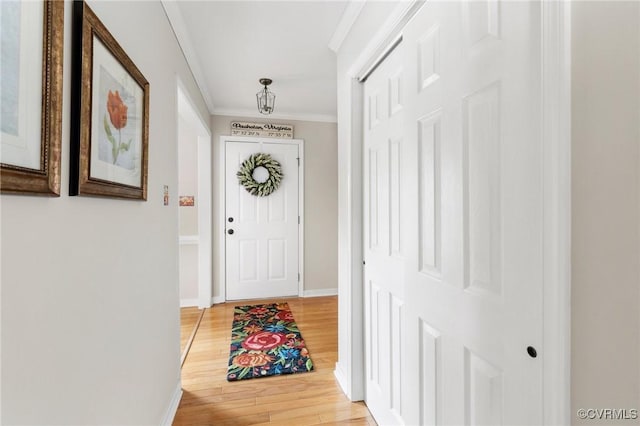 doorway with baseboards, light wood-style floors, and crown molding